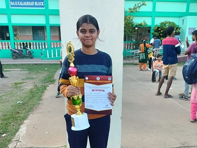 Charumathi proudly holding her chess trophy after winning a tournament match.