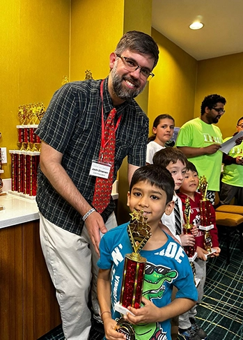 Time2Chess coach mentoring young players and celebrating their success at a chess event.